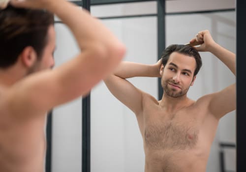 dark haired man brushing his hair at the mirror